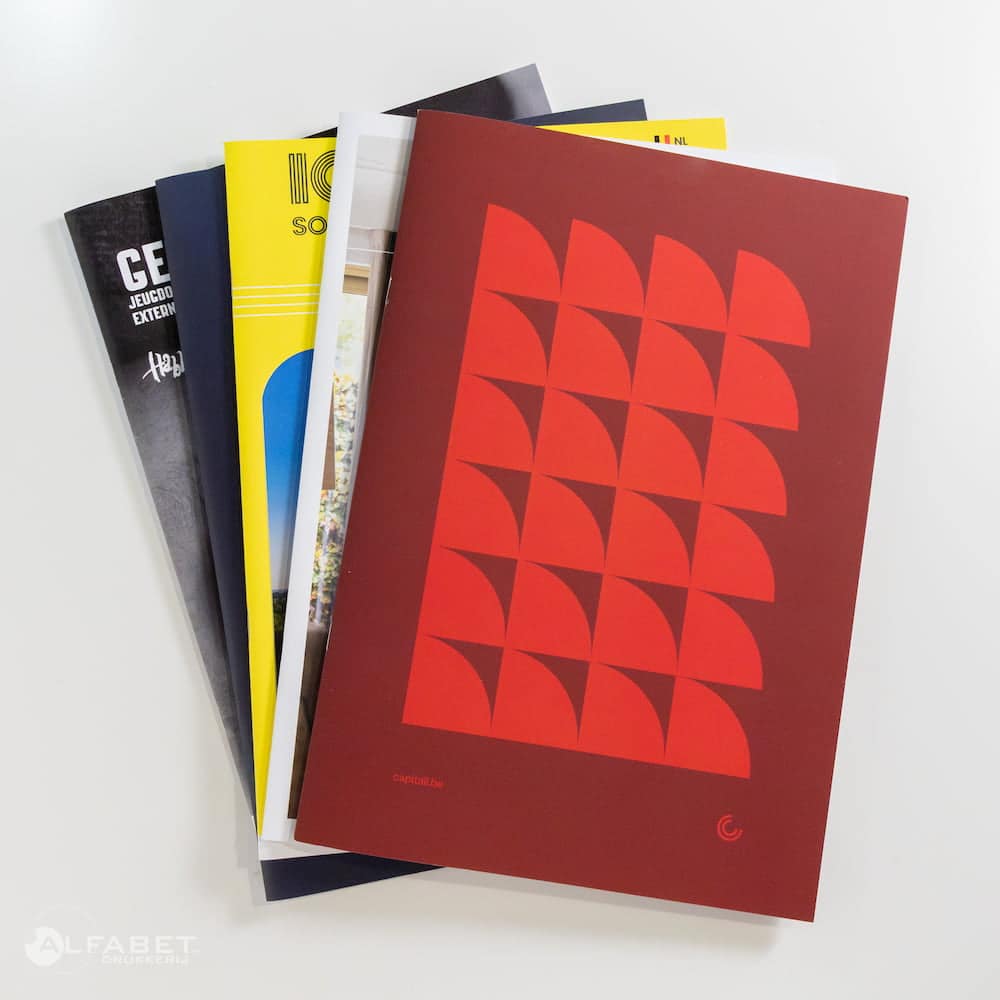 Afbeelding van een stapel van vijf geniete boeken in waaiervorm, gedrukt door drukkerij Alfabet