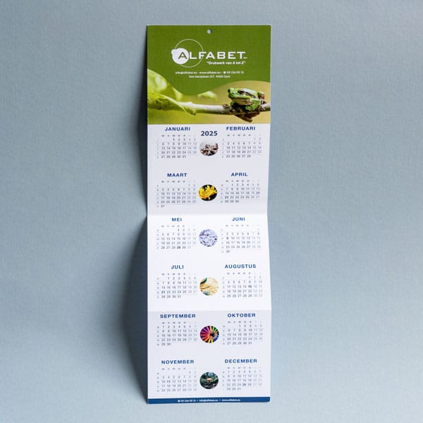 Afbeelding van een 4-luik wandkalender die volledig open is en op de muur gehangen kan worden aan de hand van een voorzien boorgat